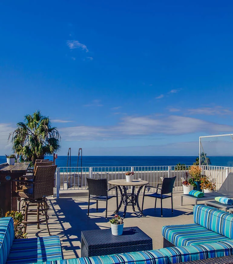 a patio with chairs and tables overlooking the ocean