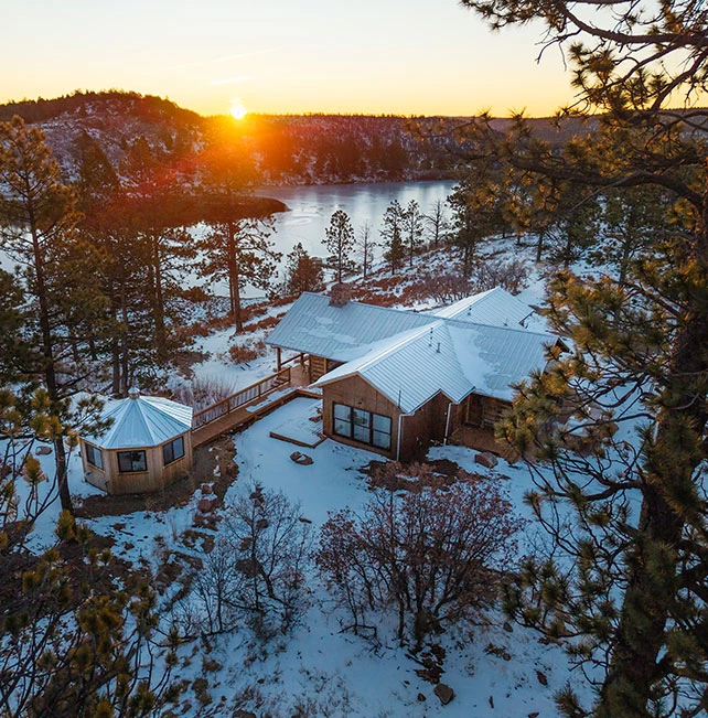 a cabin with a deck and a lake in the background