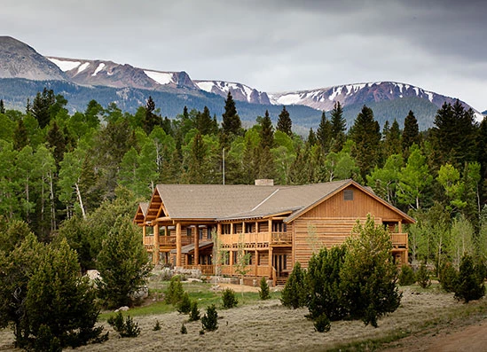 a large wooden house surrounded by trees and mountains