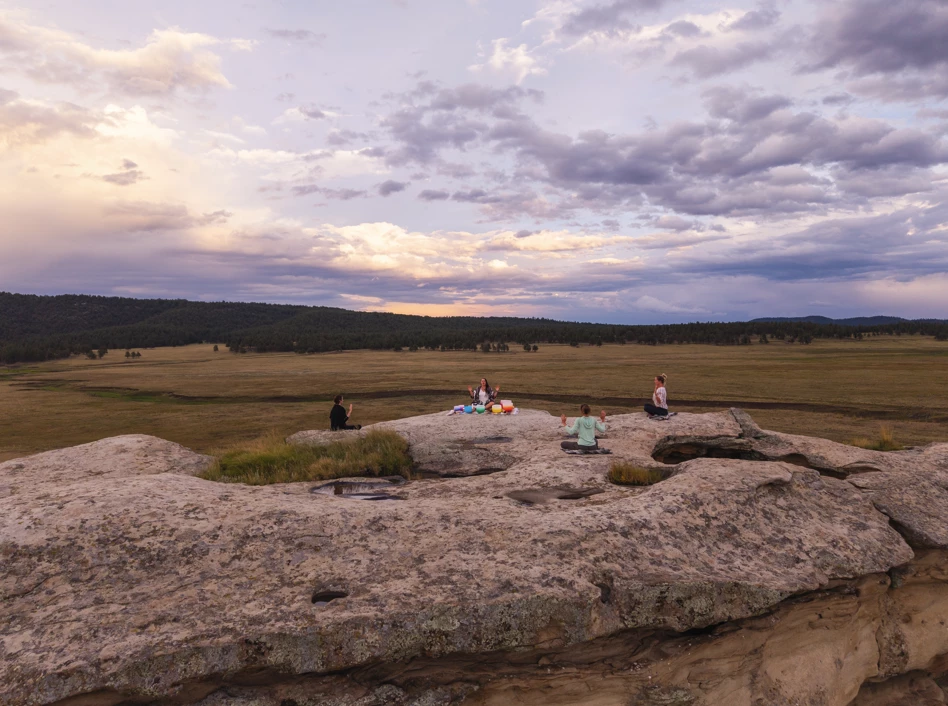 a group of people sitting on a rock in a field