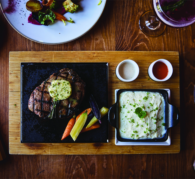 a steak and mashed potatoes on a wooden tray