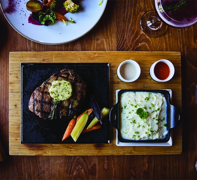 a steak and mashed potatoes on a wooden tray