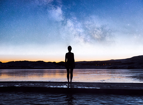 a person standing on a dock in front of a lake