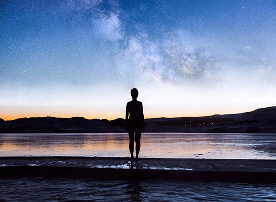 a person standing on a dock in front of a lake
