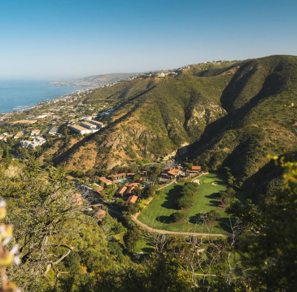 a green hills with buildings and a body of water