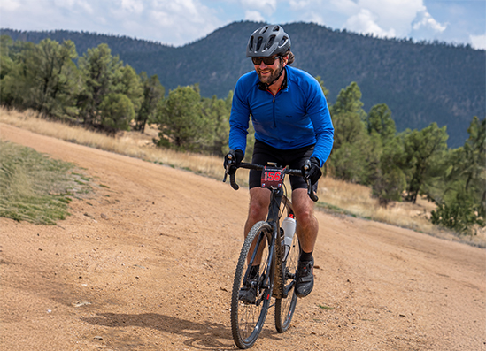 two people riding bikes on a dirt road