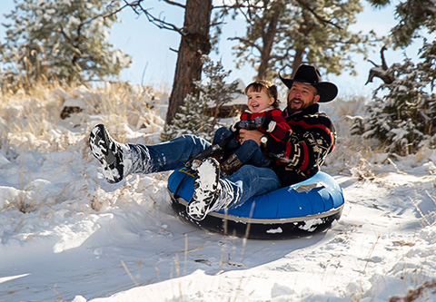 a man and child on a tubing in the snow