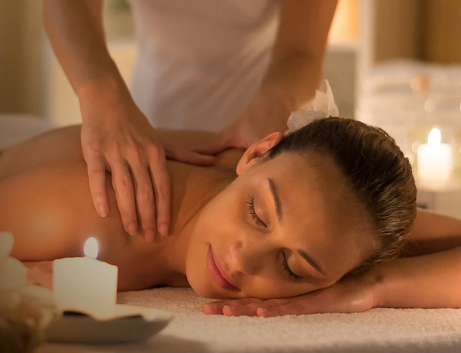 a woman lying down on a towel with a candle on the side