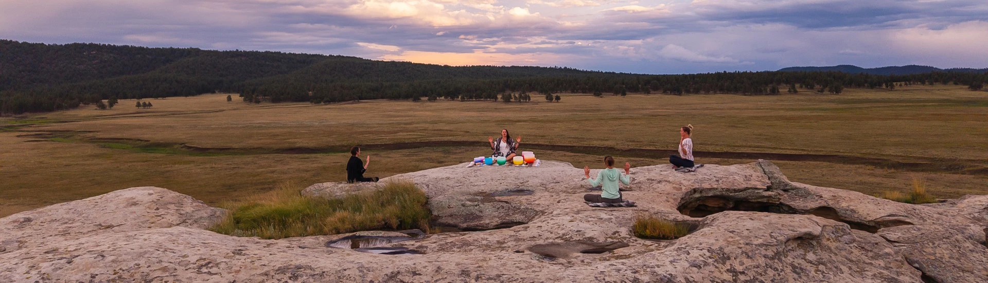 a group of people sitting on a rock with a group of people in the background