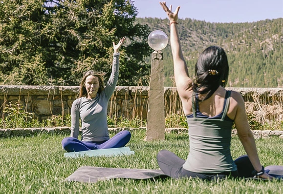 two women sitting on the grass with their hands up
