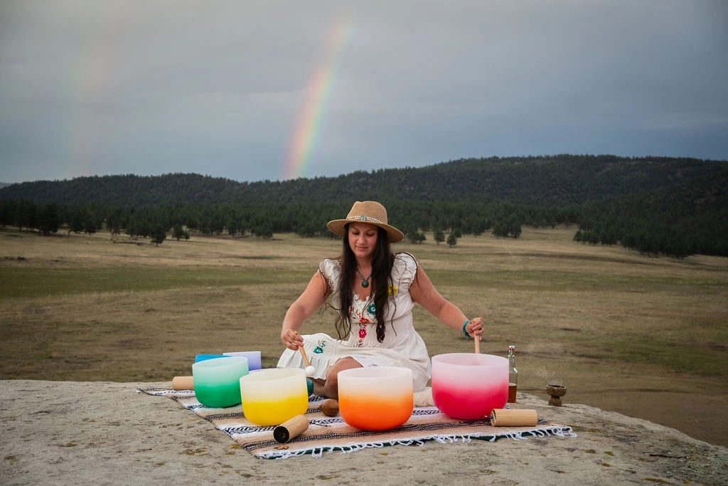 a woman sitting on a blanket with colorful bowls on it