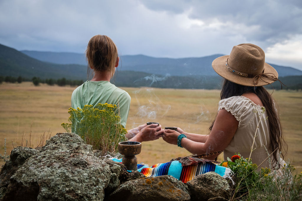 two women sitting on a blanket outside