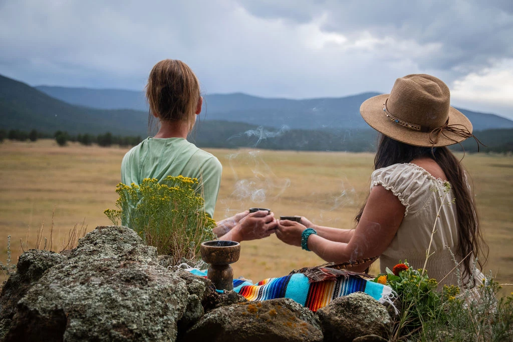 two women sitting on a blanket outside
