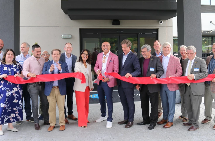 a group of people cutting a red ribbon