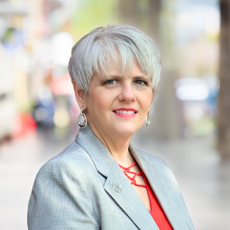 a woman with short hair wearing a suit and earrings