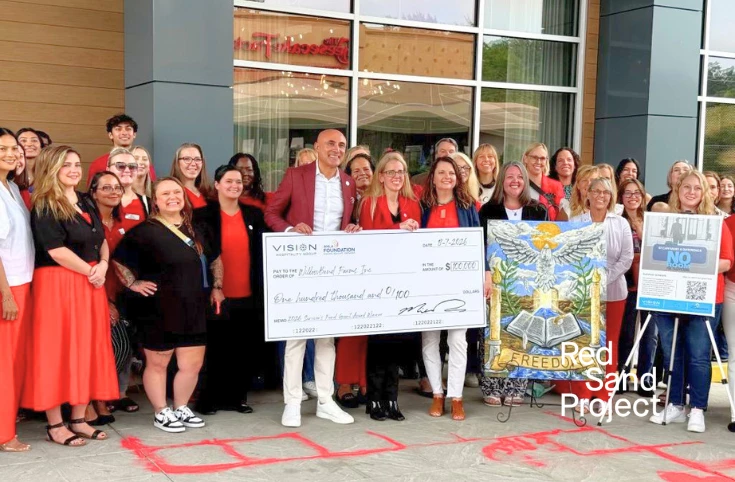 a group of people standing together holding a large check