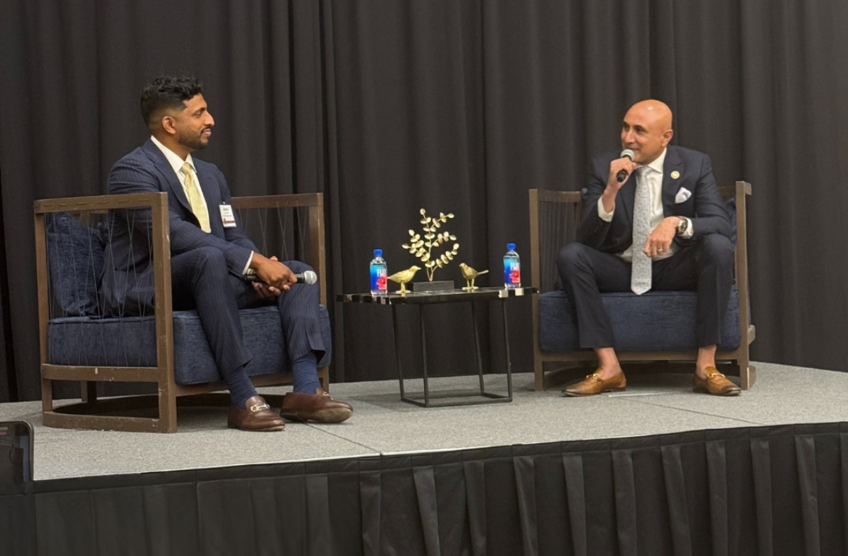 two men sitting in chairs on a stage