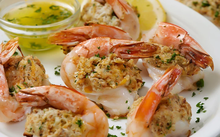 A plate of shrimp with herbs and lemon.