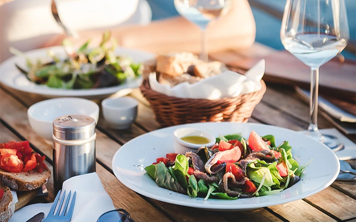 A table set with salads, bread, and wine glasses.