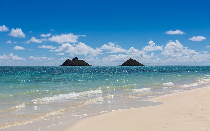 a beach with waves and islands in the distance