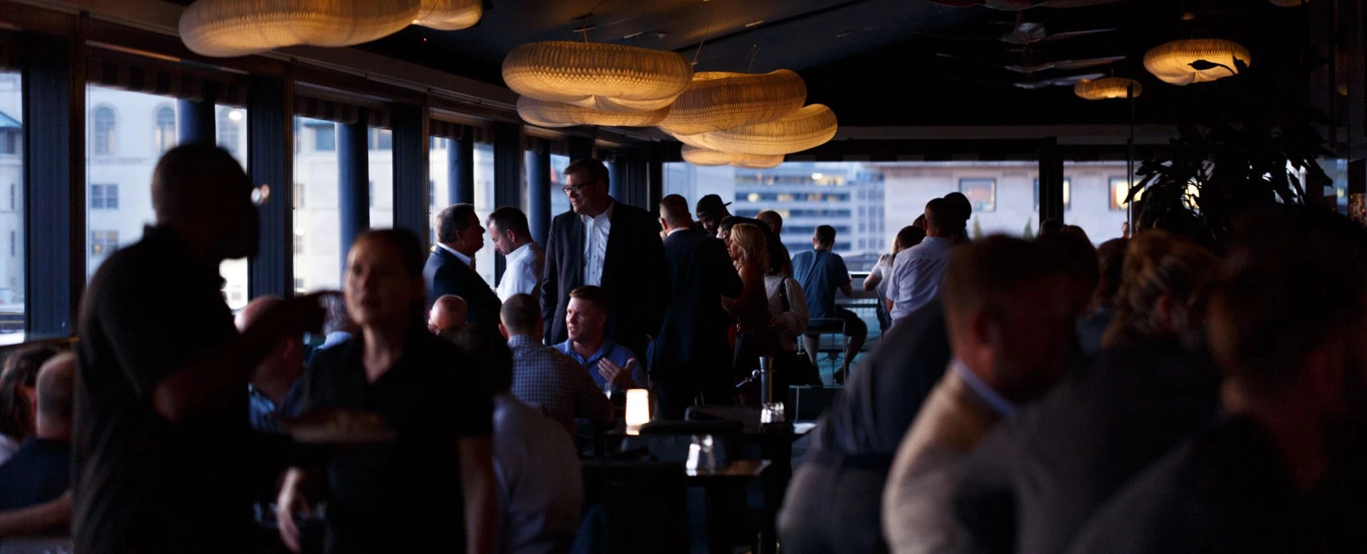 a group of people standing and sitting in a bar at night time