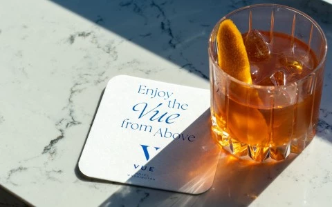 a drink with orange slice and ice on a coaster