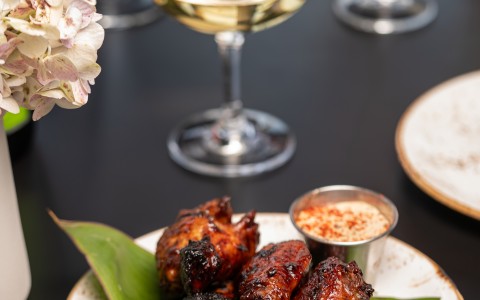 a plate of chicken wings and a glass of wine