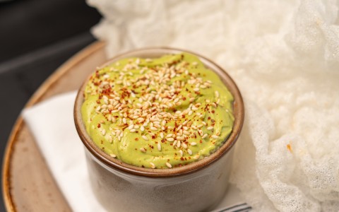 a bowl of guacamole with sesame seeds on a plate