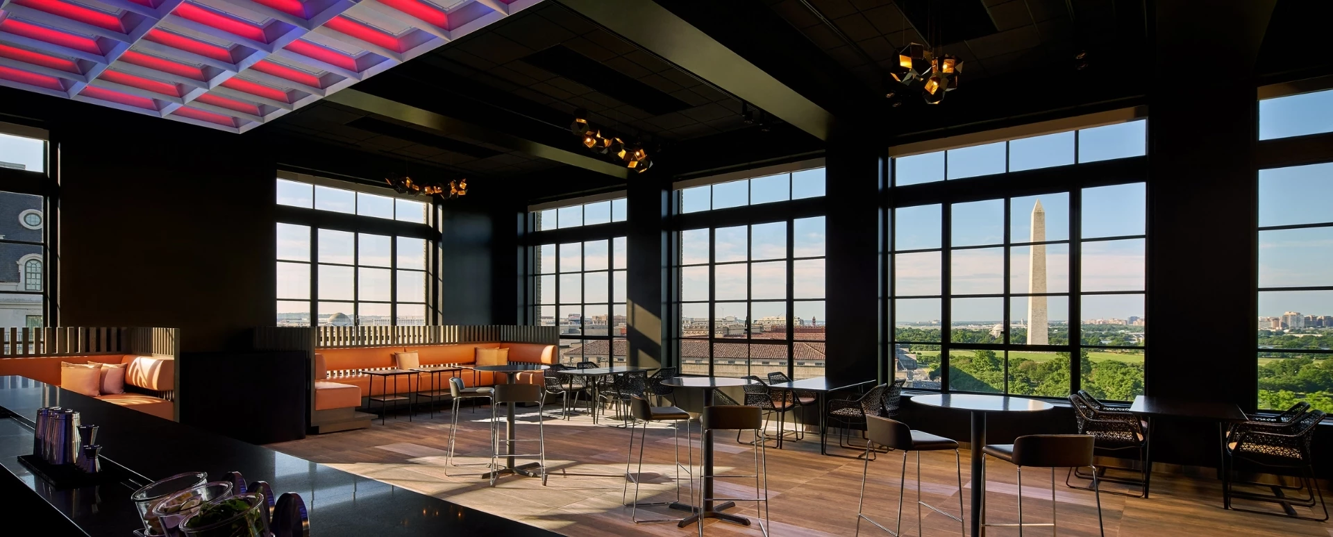 4 people clinking cocktails together with view of washington monument behind them