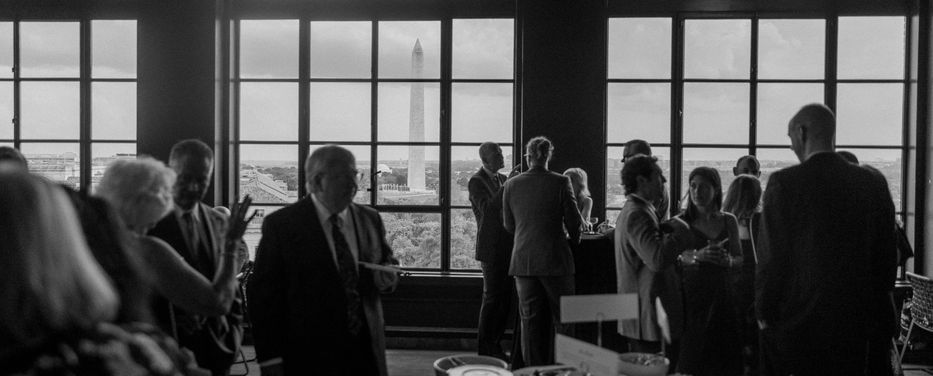 4 people clinking cocktails together with view of washington monument behind them