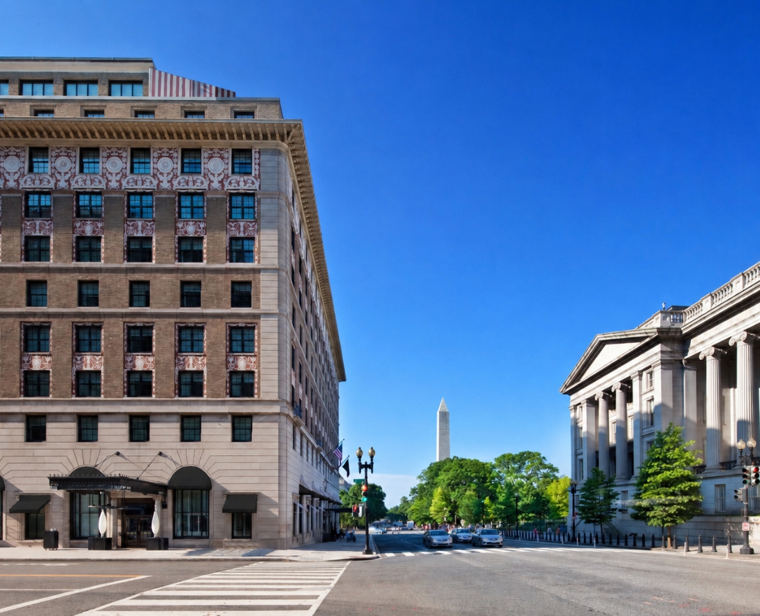 a street view of hotel washington building exterior with washinton monument in view