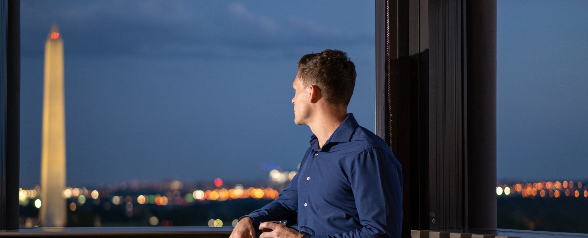 a man sitting in front of a window looking out the window