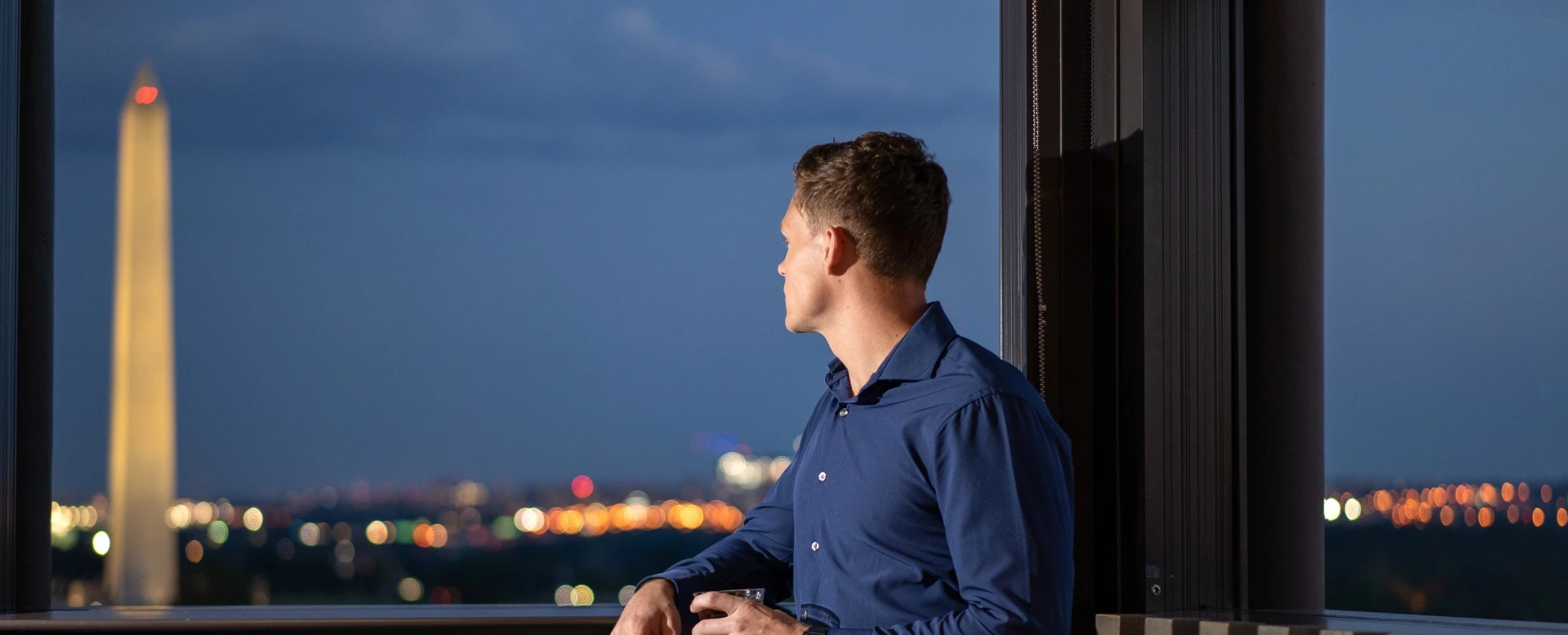 a man sitting in front of a window looking out the window