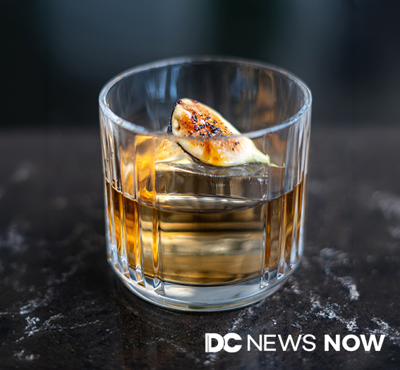 a glass with liquid and a slice of a fig on top