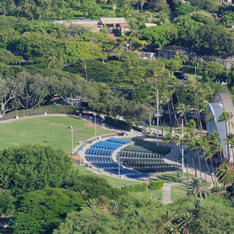 an aerial view of a park with a large stadium and trees