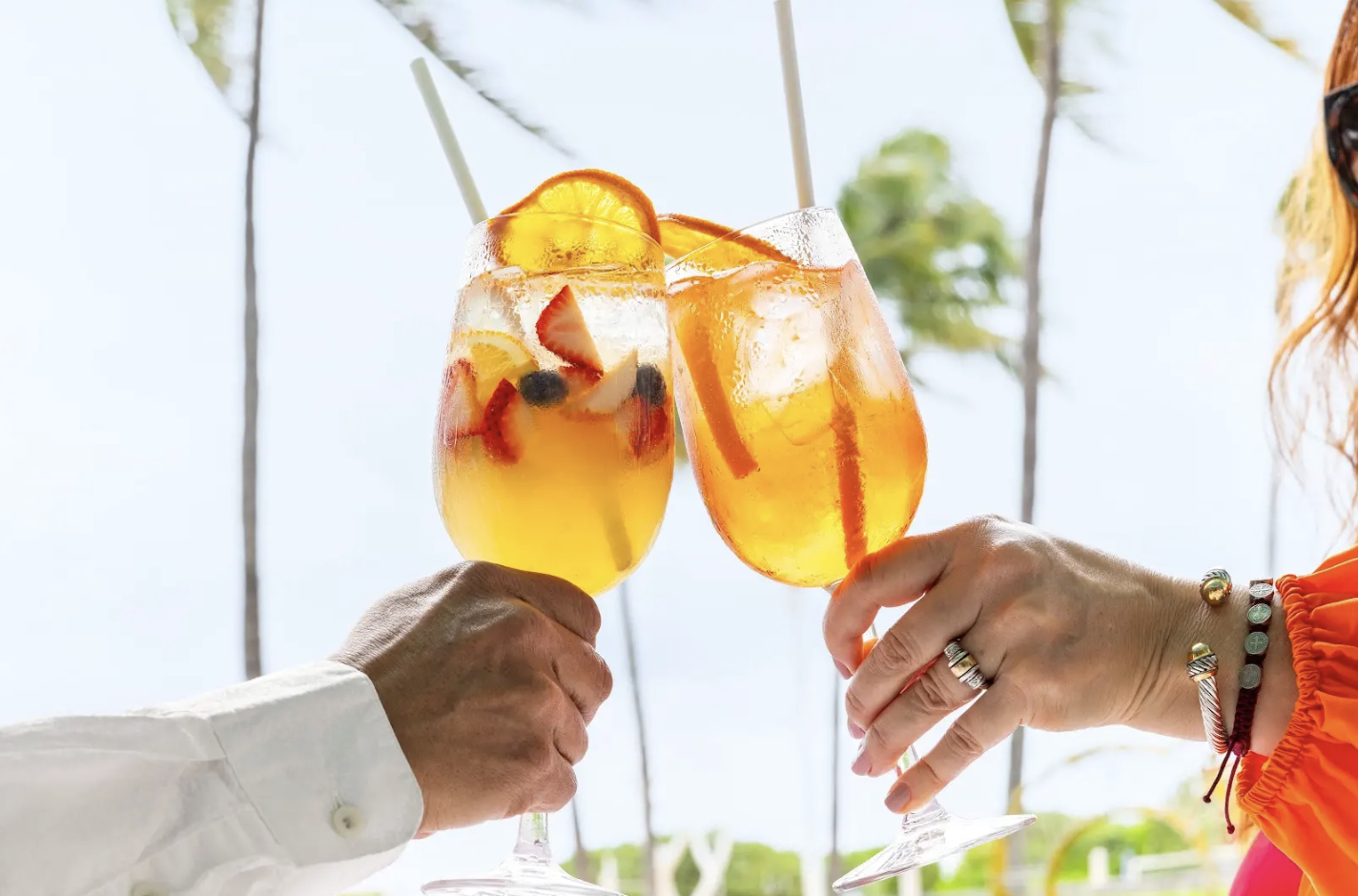 a pair of hands clinking glasses with fruit