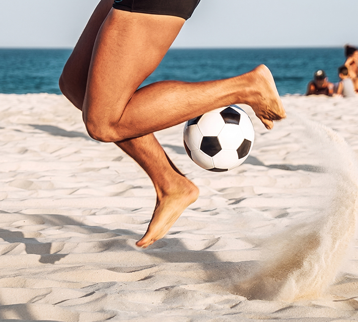 a person jumping with a football ball on a beach