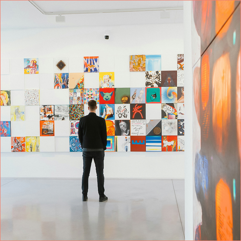a man looking at a wall of art
