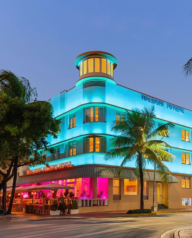 a building with palm trees and a blue and pink light