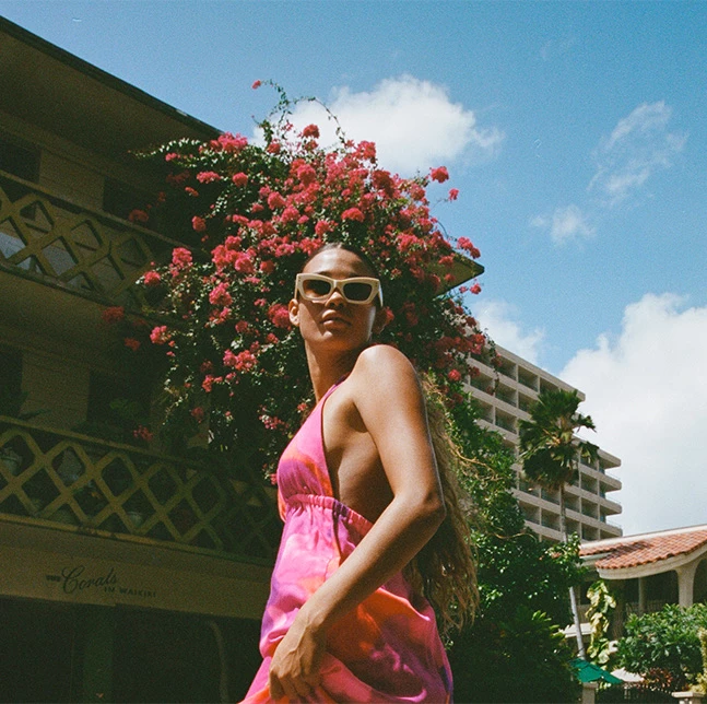 woman standing with a pink dress in front of a building