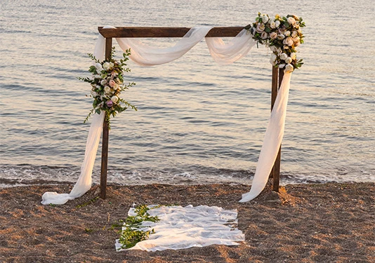 altar decorated with white fabric and flowers by the beach