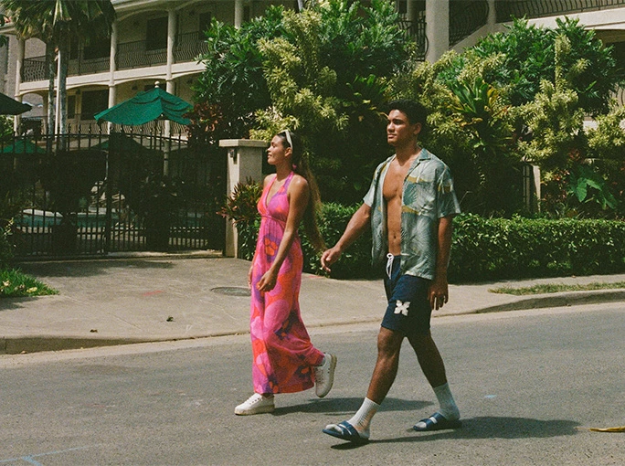 a woman with a pink dress walking by a mans side