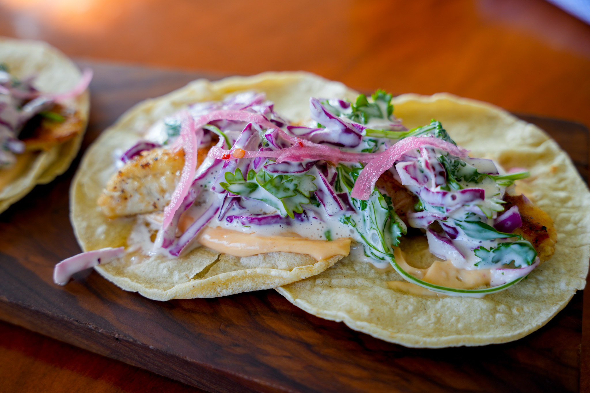 a taco with vegetables and sauce on a wooden surface