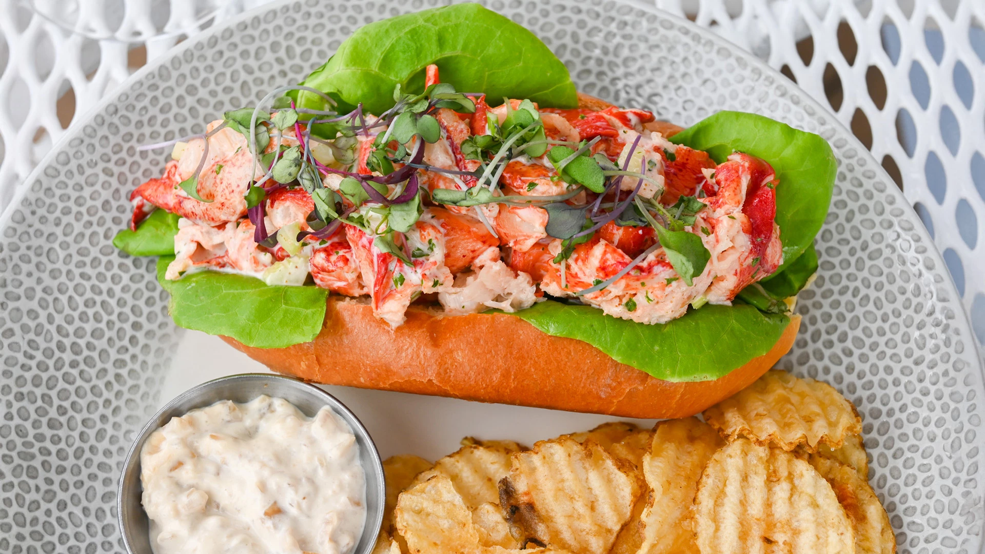 a lobster roll with lettuce and sauce on a plate