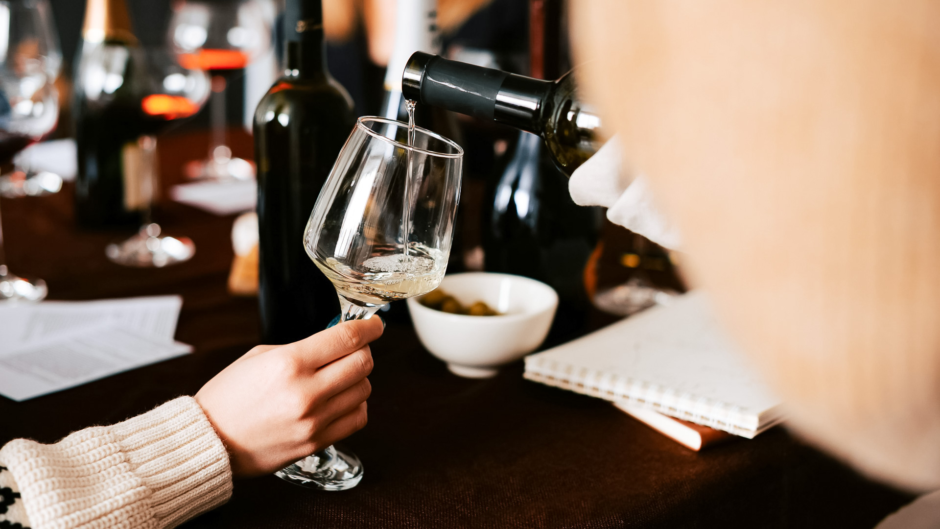 a person pouring wine into a glass