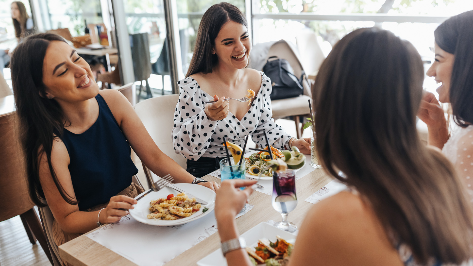 a group of women sitting at a table eating food