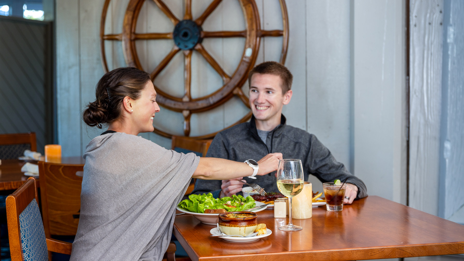 a man and woman sitting at a table with food and drinks