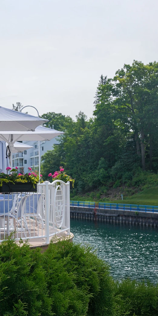 a white railing with flowers and umbrellas on a deck