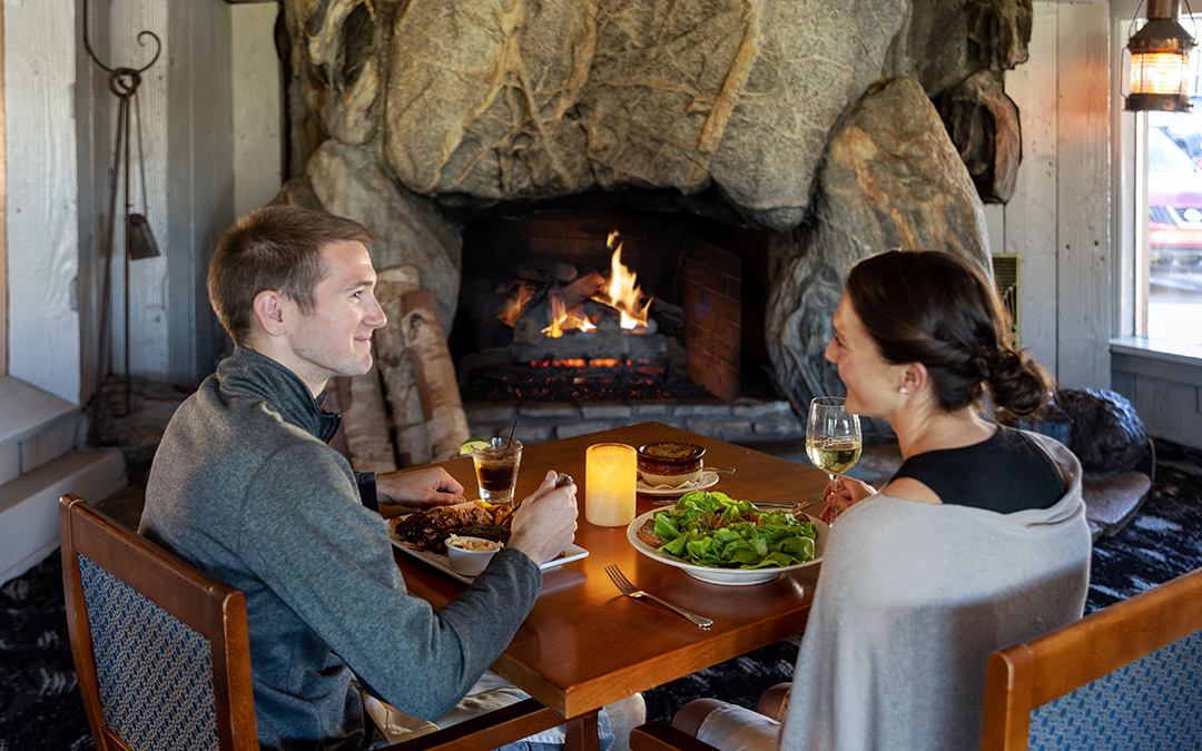 a man and woman sitting at a table with food and drinks