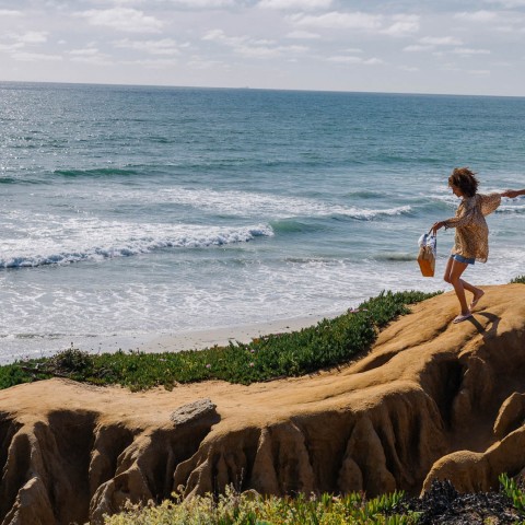 a woman walking on a cliff by the ocean